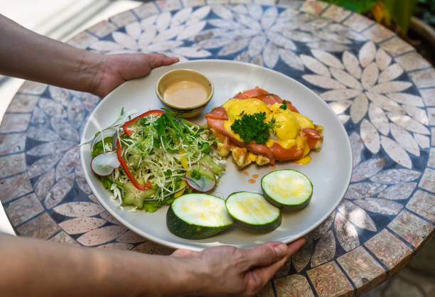 istock waitress holding a plate with eggs bennedict waffles with smoked salmon and serving on a table 1796461441