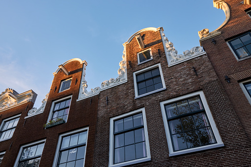 CLOSE UP: Gorgeous 17th century slim and high canal houses along Amsterdam waterway opened as museums, offices and hotels. Famous buildings with historic facades, skinny profile and grand gables