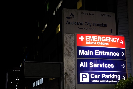 Auckland, New Zealand – September 15, 2023: The Auckland City Hospital directional sign at night with arrows pointing in multiple directions