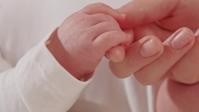 Close up video of mother holding baby hand