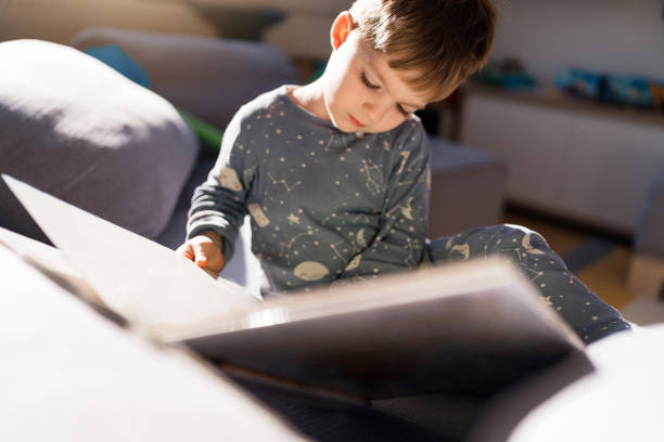 istock Curious Caucasian toddler boy reading a child book 1796475419