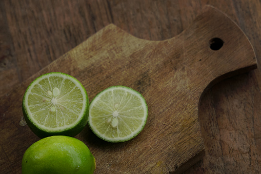 Green lime sliced ​​on a cutting board on a wooden table