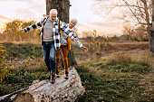 Senior couple walking on a tree log in forest
