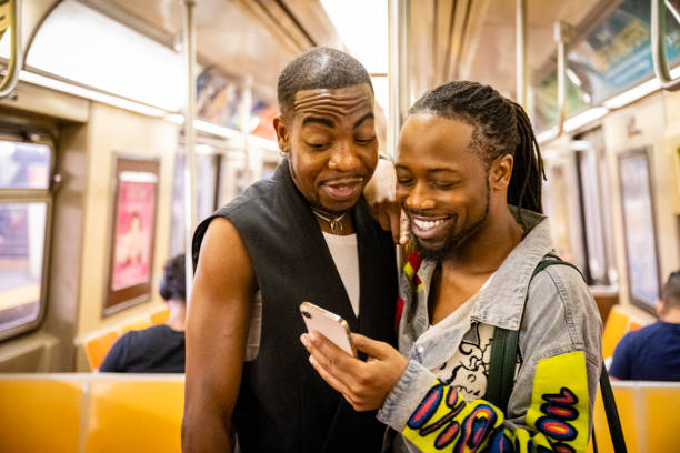 istock Smiling gay couple standing in A train interior using device 1796516771