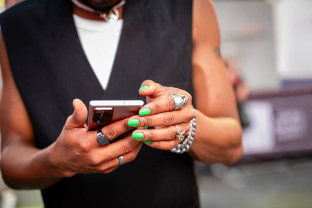 Gay Black man with green nail polish using smart phone