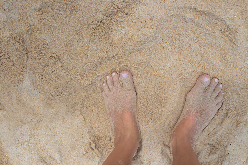 Women's feet in the sand on the beach. Health and rest.