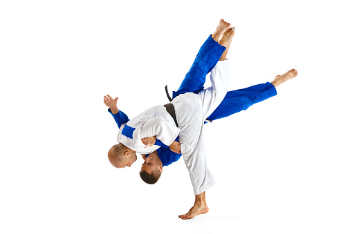 Two professional sportsmen, athletic men in in white and blue uniform performing technical skills while fighting isolated white studio background. Concept of combat sport, energy, fit. Copy space, ad