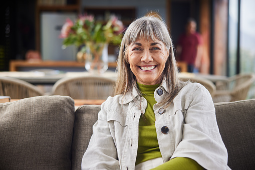 Mature woman smiling while relaxing on a sofa in the living room of her luxury home