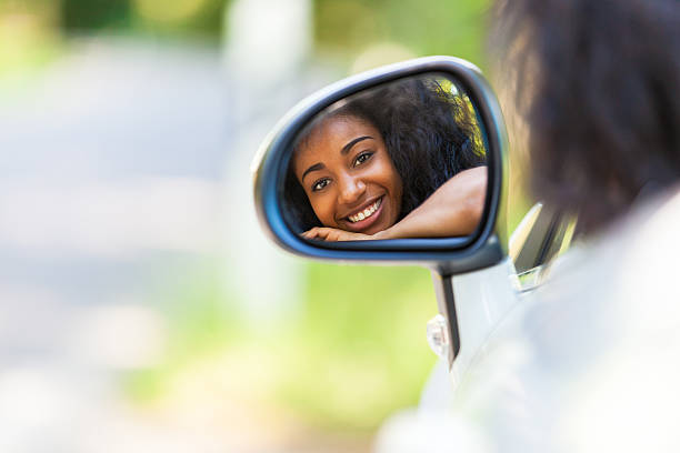 A teenager in the rear view mirror of her new convertible stock photo