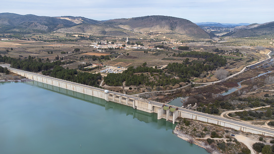 Rear view of the Bellus dam dedicated to containing water for irrigation and against possible floods and in the background the town of Bellus between mountains, in the province of Valencia, Spain. Civil engineering concept