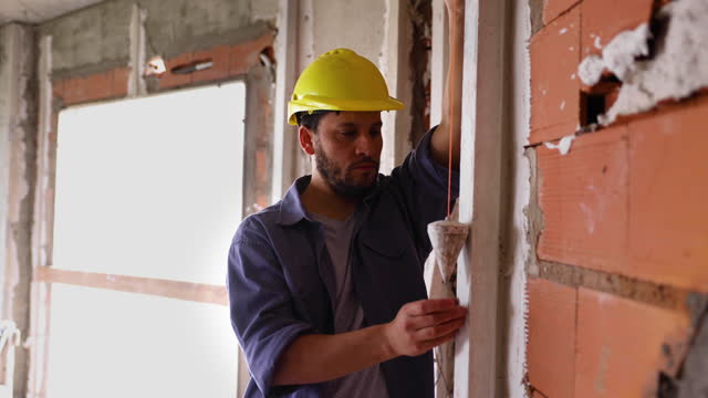 Blue collar worker at a construction site using a pendulum looking very focused