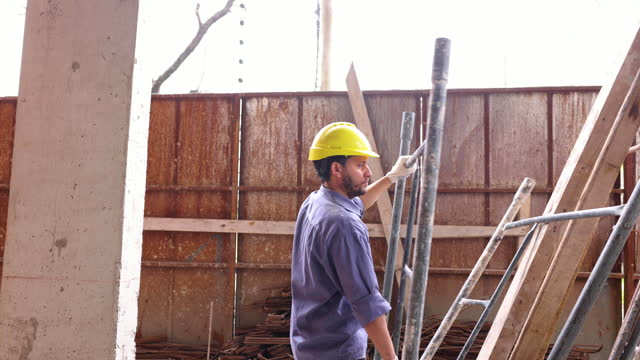 Latin American worker at a construction site carrying a scaffold