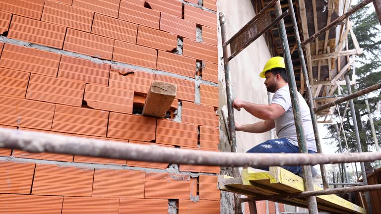 Latin American worker standing on a scaffold cementing a wall