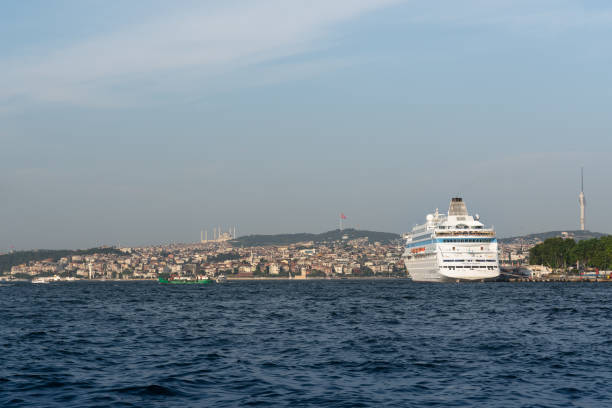ISTANBUL, TURKEY – October 31, 2025: A municipal passenger ferry departs a Bosphorus pier on a glittering sea under cloudy skies, with the historic peninsula skyline—Hagia Sophia and the Blue Mosque visible in the background.
