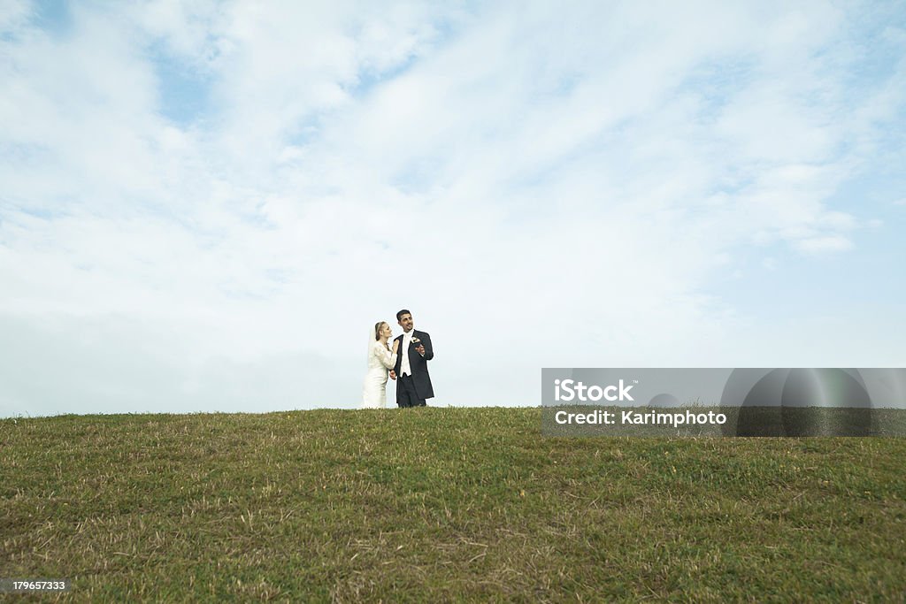 Bride and groom on a hill Happy bride and groom in wedding attire before their wedding. He in a classic tuxedo and she in a white Lace Dress. Adult Stock Photo