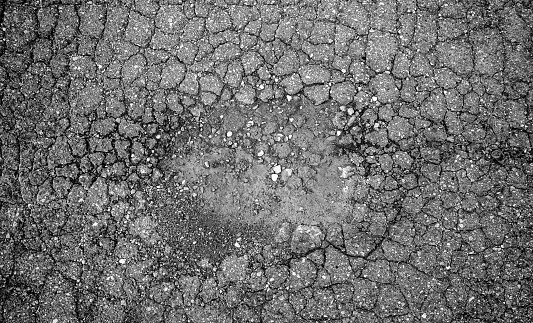 Detail of old asphalt broken and cracked by the passage of time, ruin and abandonment