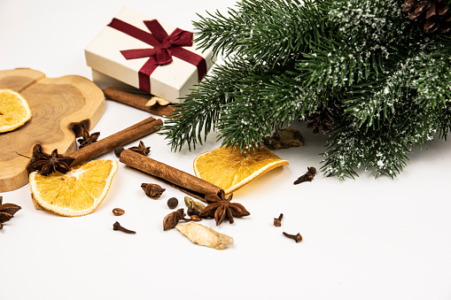Christmas composition with Christmas tree, dried oranges, cinnamon, ginger, gift box, anis and wood\nStill life