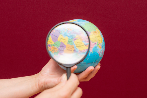 Conceptual image of a hand holding a magnifying glass over an world globe