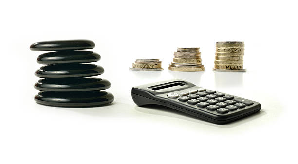 Financial Balance 2 A concept image relating to financial matters. Stacked coins representing investments, pension or savings with Feng Shui black stones representing balance. Generic calculator.  White background with copy space. golden nest egg taxes stock pictures, royalty-free photos & images