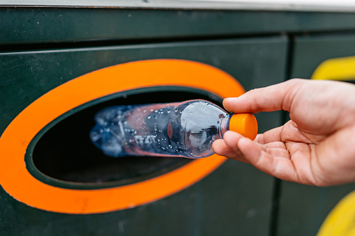 Close-up of a young man putting a water bottle in a recycling bin in Malmo in Sweden.