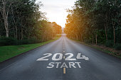 Happy new year 2024,2024 symbolizes the start of the new year. The letter start new year 2024 on the road in the nature route roadway have tree environment ecology or greenery wallpaper concept.