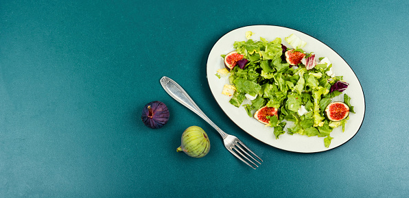 Autumn healthy salad with figs, herbs and cheese. Space for text. Banner.