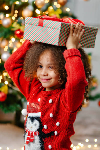 istock A Black girl holds a Christmas gift on her head 1796611896