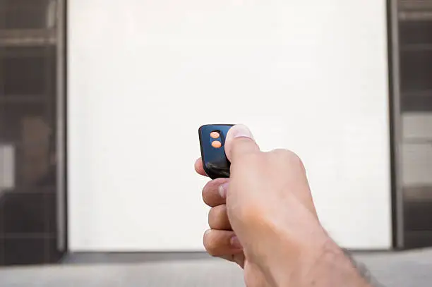 hand pressing a remote control with the door closed