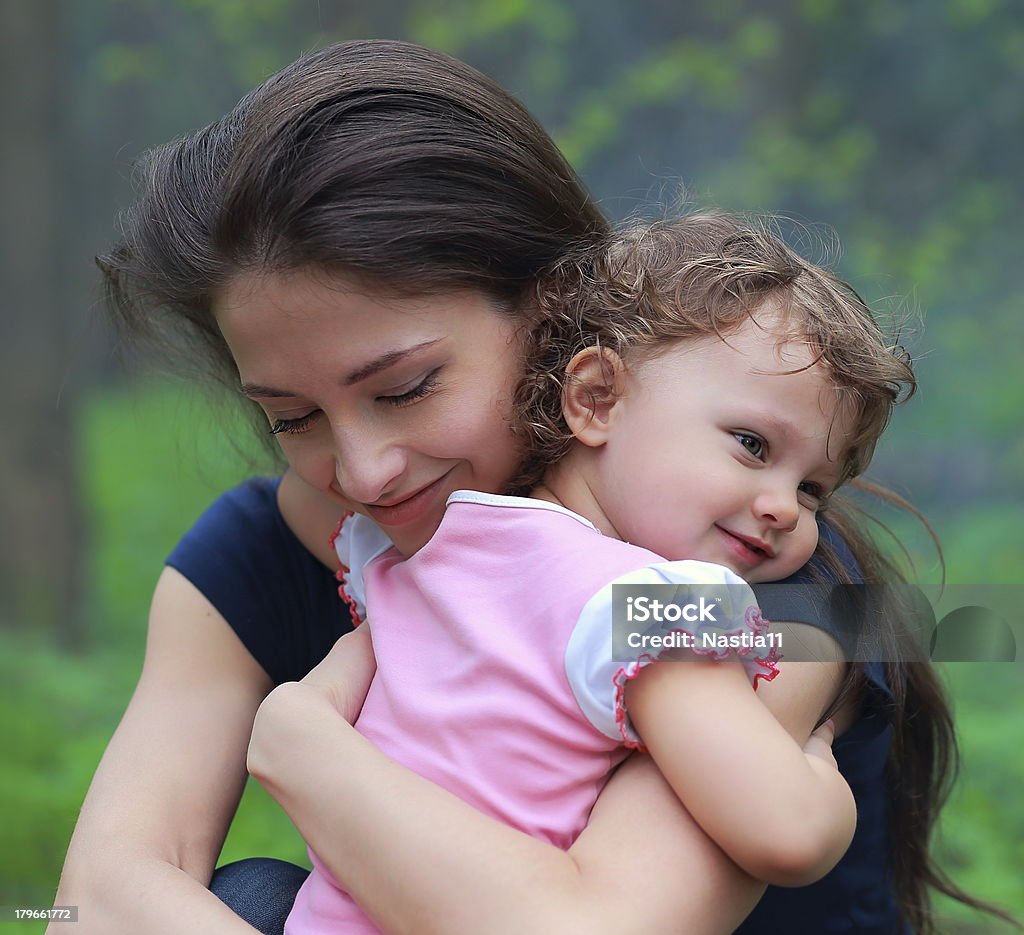 Smiling happy mother and cute kid girl cuddling outdoor Smiling happy mother and cute kid girl cuddling outdoor summer background. Closeup tender and love portrait Adult Stock Photo