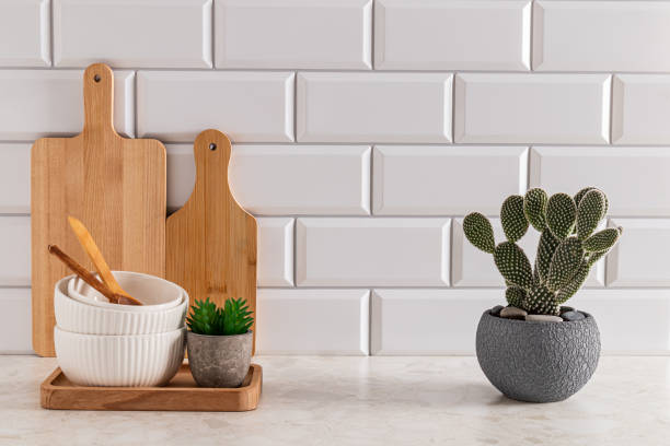 istock Set of ceramic bowls and cutting boards on stone light countertop in modern kitchen with potted opuntia, cactus . Front view. minimalism. 1796620011