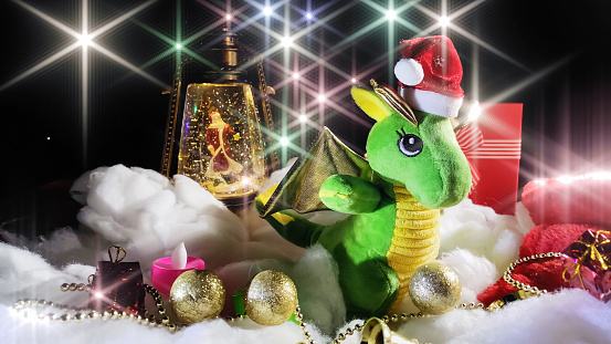 Green dragon symbol of 2024 new year, Christmas lantern with Santa Claus with decoration, shimmering background. Holiday celebration concept.