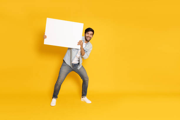 istock Young man showing and holding blank white billboard isolated on yellow background 1796647922