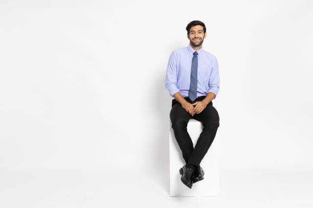 istock Young businessman sitting on white box and smiling isolated on white background 1796648510