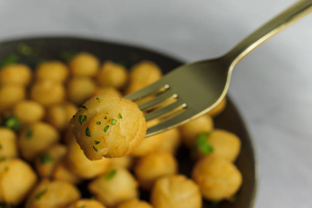 istock Duchess potatoes, on fork, homemade, typical in chile, with parsley, close up, round plate, with more potatoes, on white background. Typical Chilean food concept 1796649074