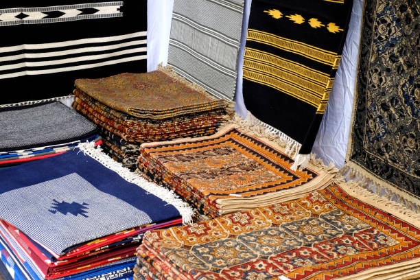 istock Carpet being rolled and displayed at a carpet exhibition in pune, Kashmir Floral design Silk Carpet, Stack of multicolored quality rugs, make in India. 1796649690