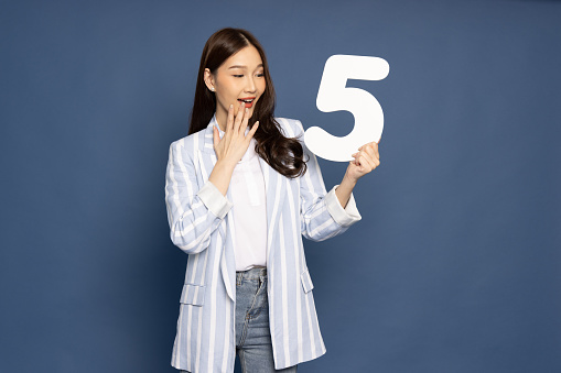 Young Asian business woman showing number 5 or five isolated on blue background