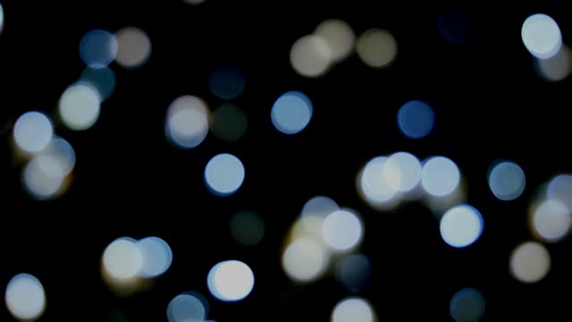 Footage defocused blurry panning motion of white blinker lights bokeh of Christmas and New year decoration lights, abstract, dark background, overlay for party, shallow DOF