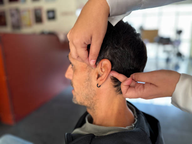 istock Woman’s hands placing a hearing aid on a Deaf man 1796760331