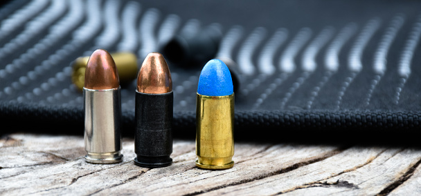 9mm pistol bullets on dark wooden plank background, soft and selective focus.