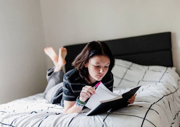 istock Transgender non binary teenager writes or draws in notebook or diary lying on their bed at home in concentration 1796785222