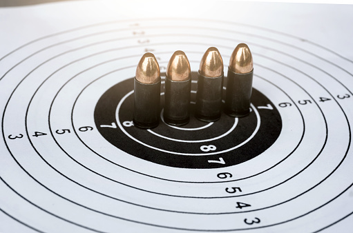 9mm pistol bullets on target shooting paper background, soft and selective focus.