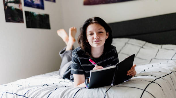 istock Transgender non binary teenager writes or draws in notebook or diary lying on their bed at home 1796790231