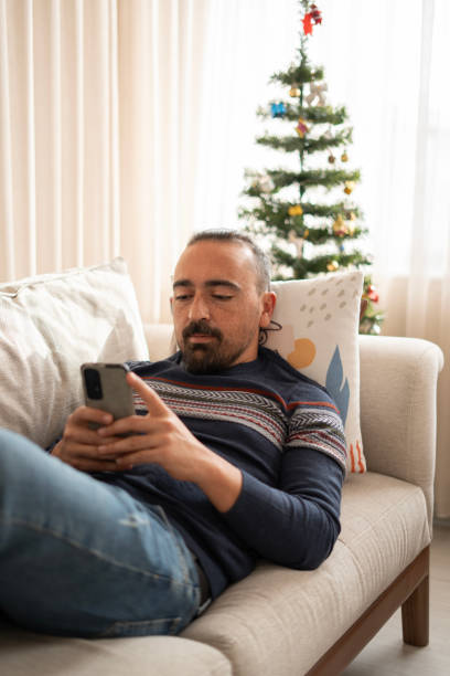 istock Young adult man lying on sofa at home and using phone 1796818558