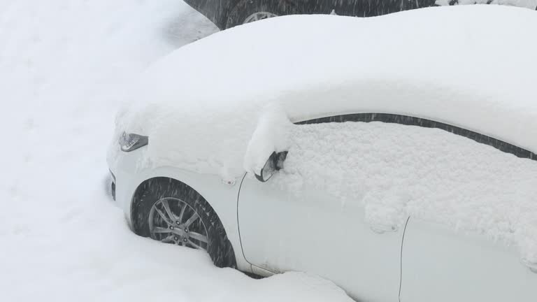 Heavy winter snowfall sweeps white car standing on street. Weather disasters. Global climate change. State of emergency.