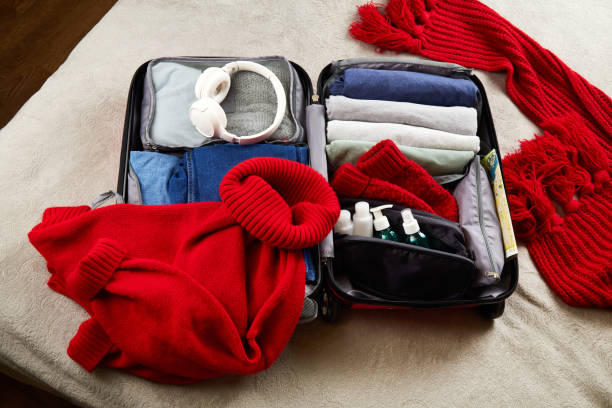 une valise ouverte avec des vêtements chauds, des documents et des accessoires pour les voyages d’hiver - pull cart photos et images de collection