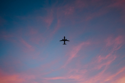 The dark silhouette of a plane in the sky.