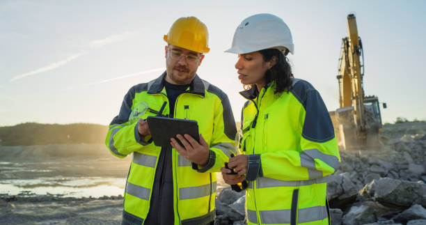 istock Caucasian Male Civil Engineer Talking To Hispanic Female Inspector And Using Tablet On Construction Site of New Apartment Building. Real Estate Developers Discussing Business, Excavators Working. 1796832155