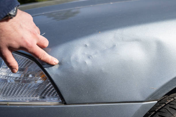 Professional automotive painting technician in chemical protecting suit inspecting car painting quality in painting chamber together. Car painting and detailing technicians portrait.
