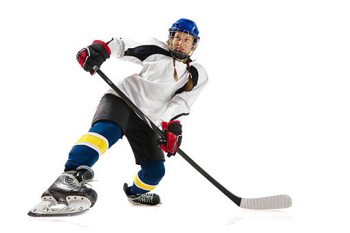 Young girl, hockey playing in helmet, uniform, with stick training, playing isolated over white background. Concept of professional sport, competition, game, action, hobby, achievements