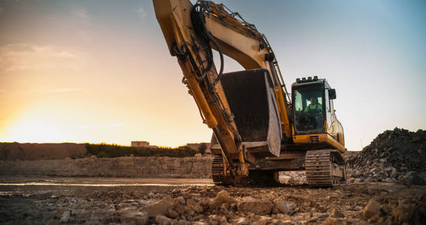 istock Construction Site On Sunny Evening: Industrial Excavator Driving To Complete Work Tasks Related To Building New Real Estate Project. Man Operating Heavy Machinery To Build New Apartment Complex. 1796841951